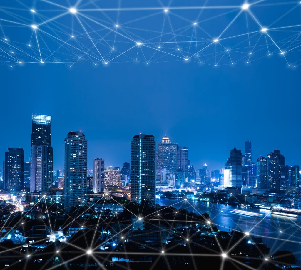 Edifícios iluminados em uma cidade inteligente conectada por tecnologia, destacando a importância da videovigilância para a segurança pública e cidades seguras.